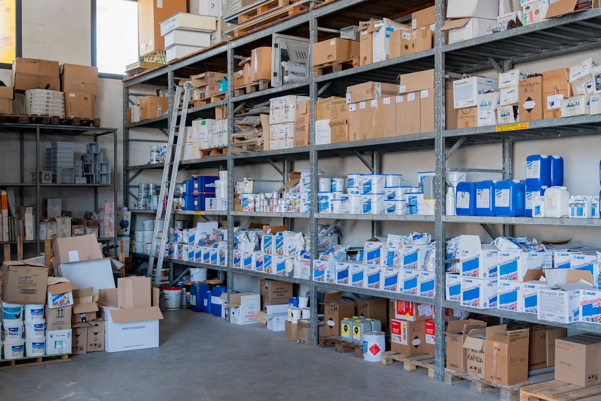 Scaffali di magazzino pieni di scatole di forniture e pacchi blu e bianchi in un locale di stoccaggio industriale.
