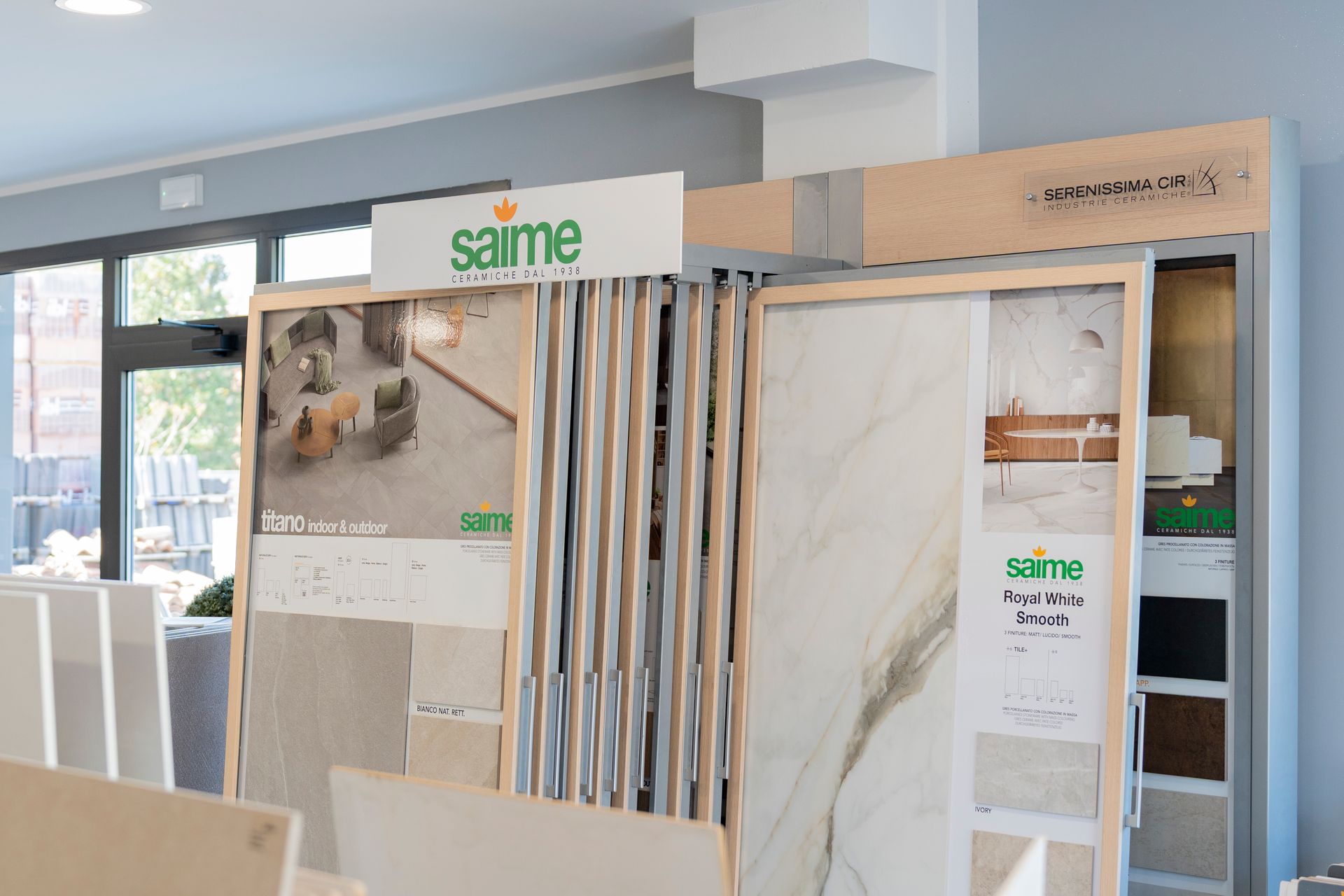 Esposizione in showroom di grandi campioni di piastrelle o pietre, con la stessa insegna del marchio e scaffalature in legno.