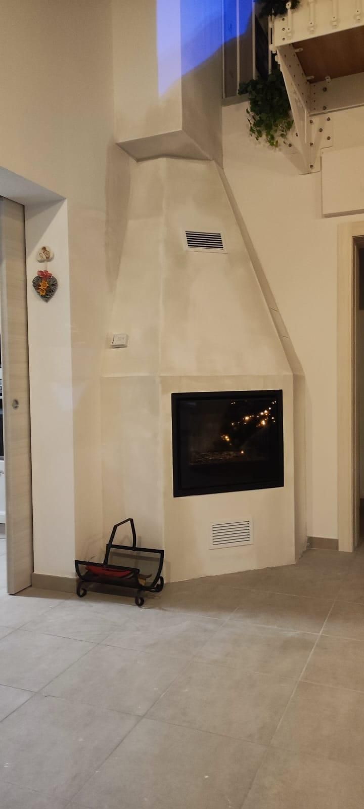 Camino interno e parete in stucco beige con una piccola scaletta e prese d'aria a muro in un angolo della stanza