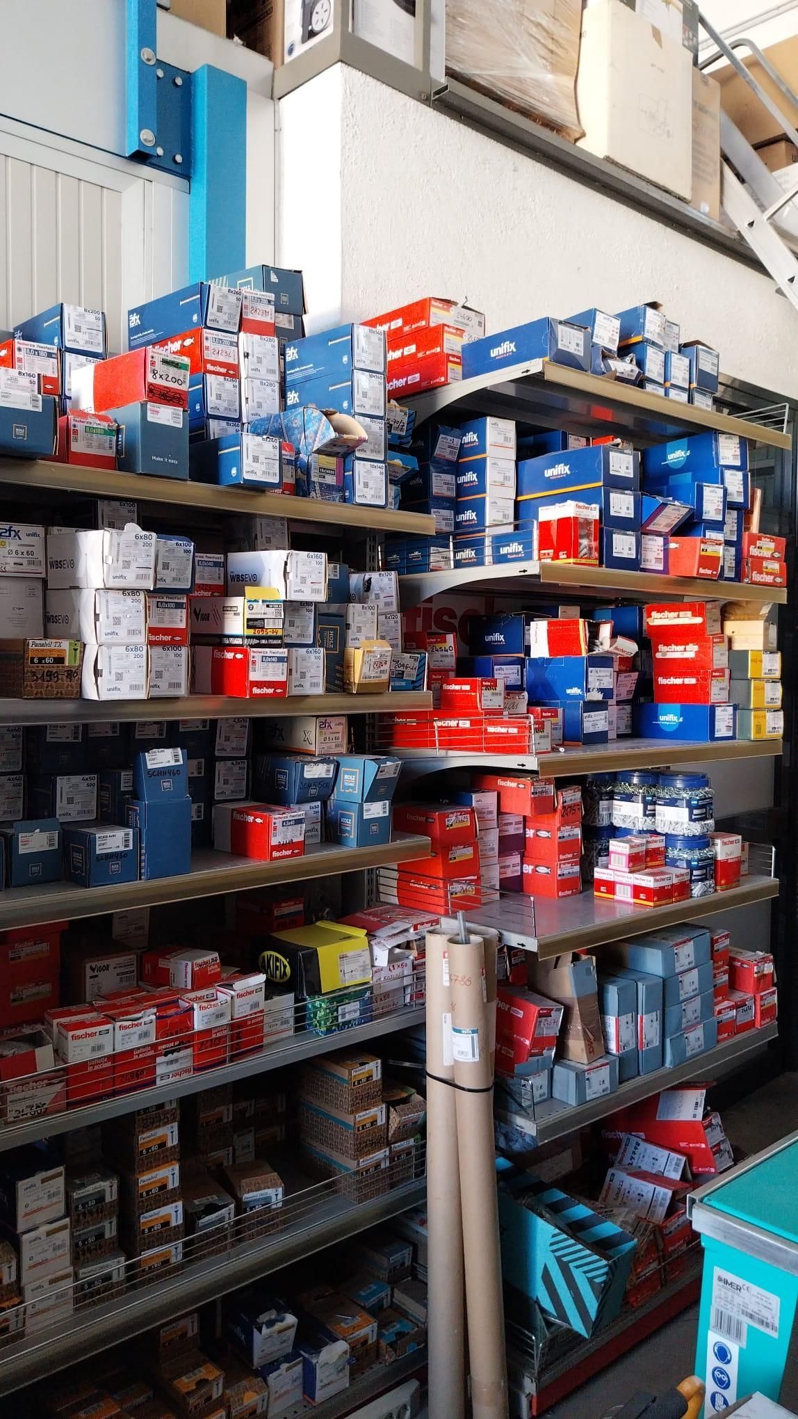 Scaffali industriali pieni di scatole assortite rosse, blu e bianche in un corridoio di un magazzino.