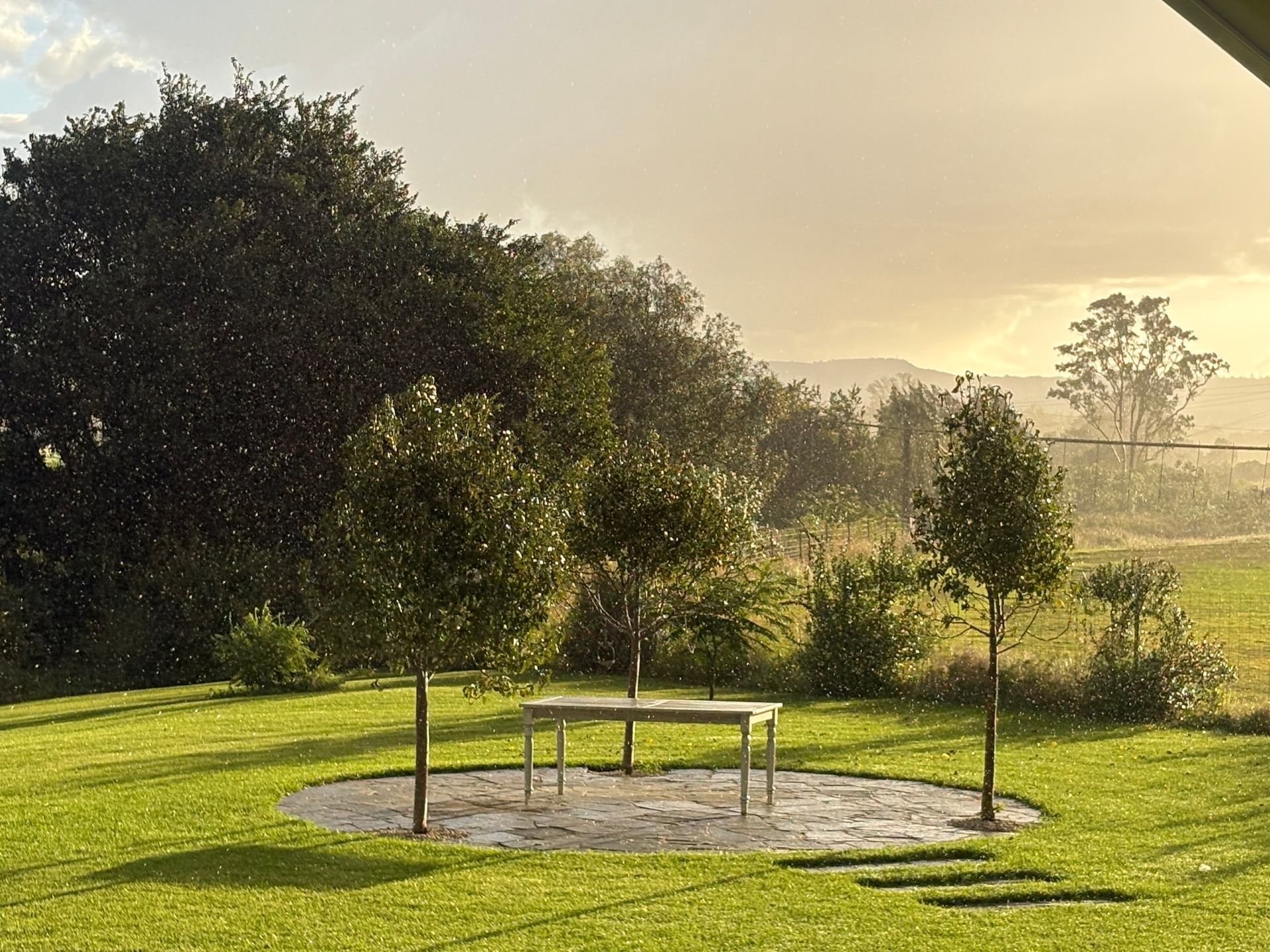 A Sunny Outdoor Scene With a Circular Stone Patio — Placid Hills Turf in Helidon, QLD