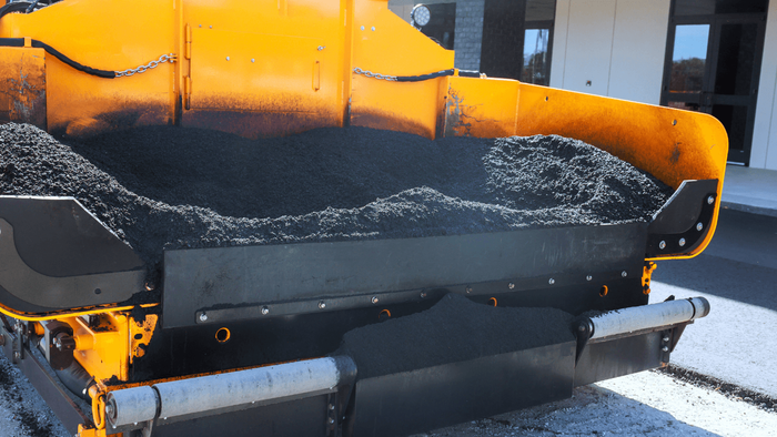 Hot asphalt being loaded and spread inside a paving machine hopper during an asphalt paving service in Arvada, CO