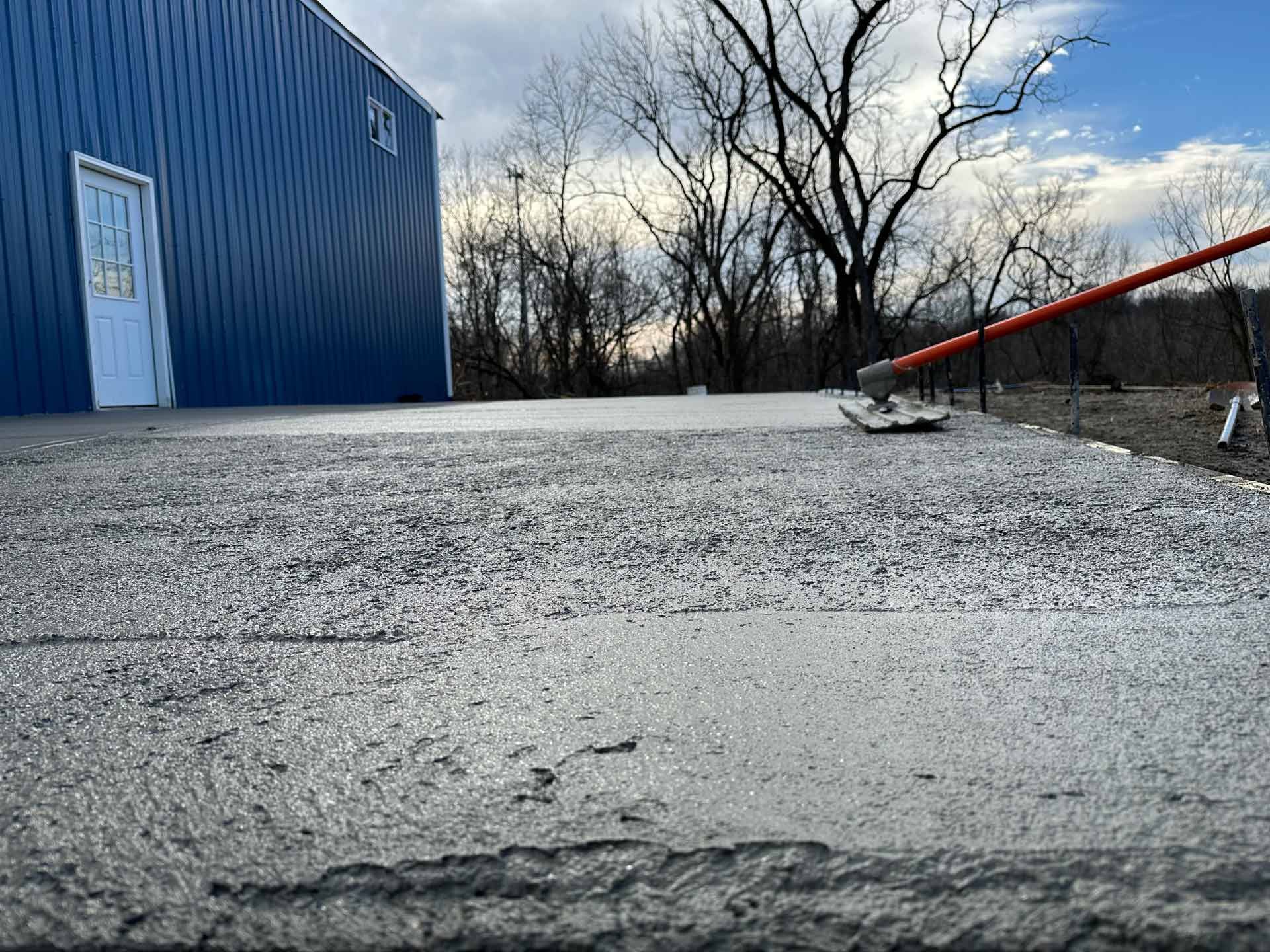 A concrete driveway is being built in front of a blue building.