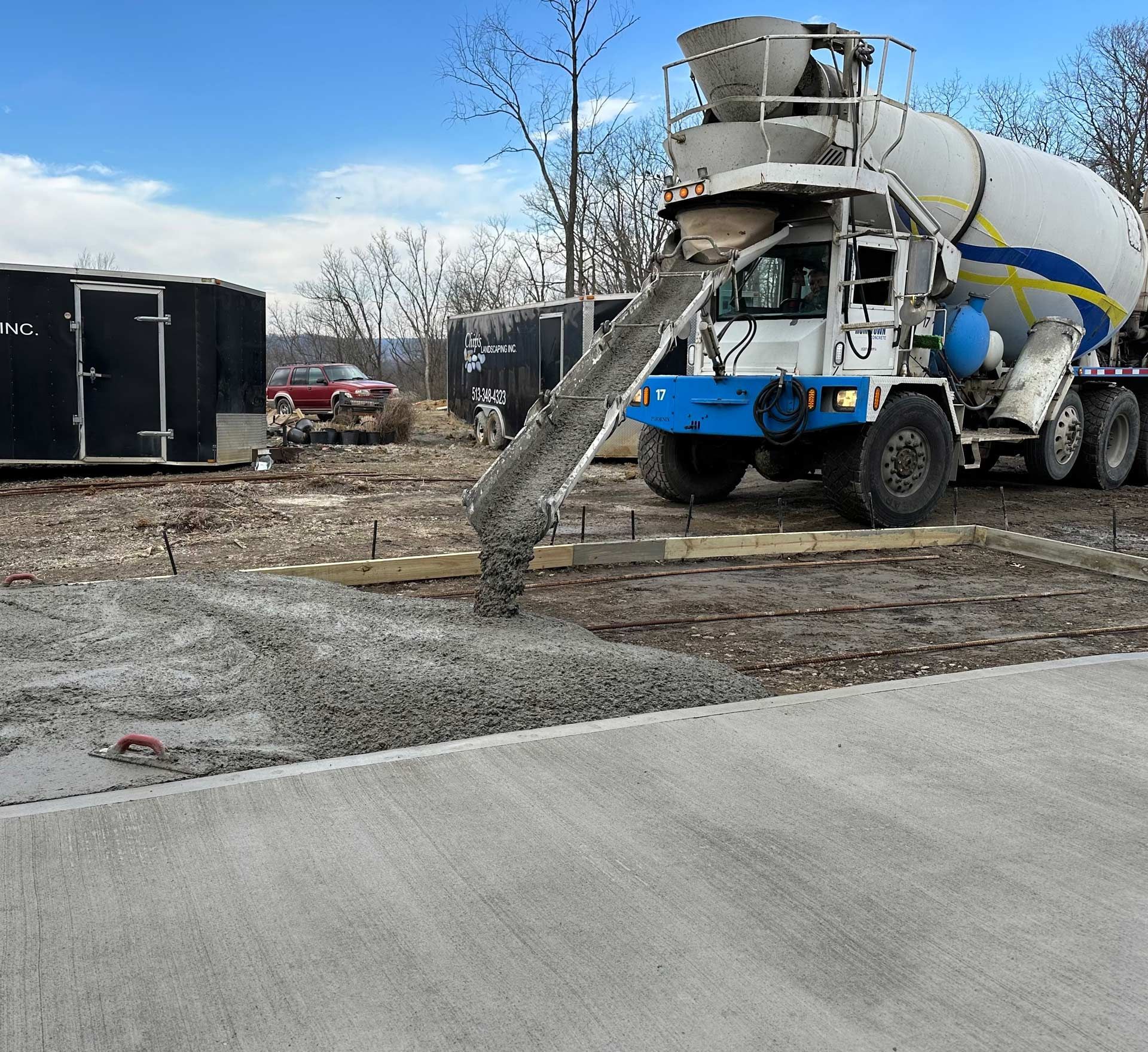 A blue and white concrete mixer truck is pouring concrete