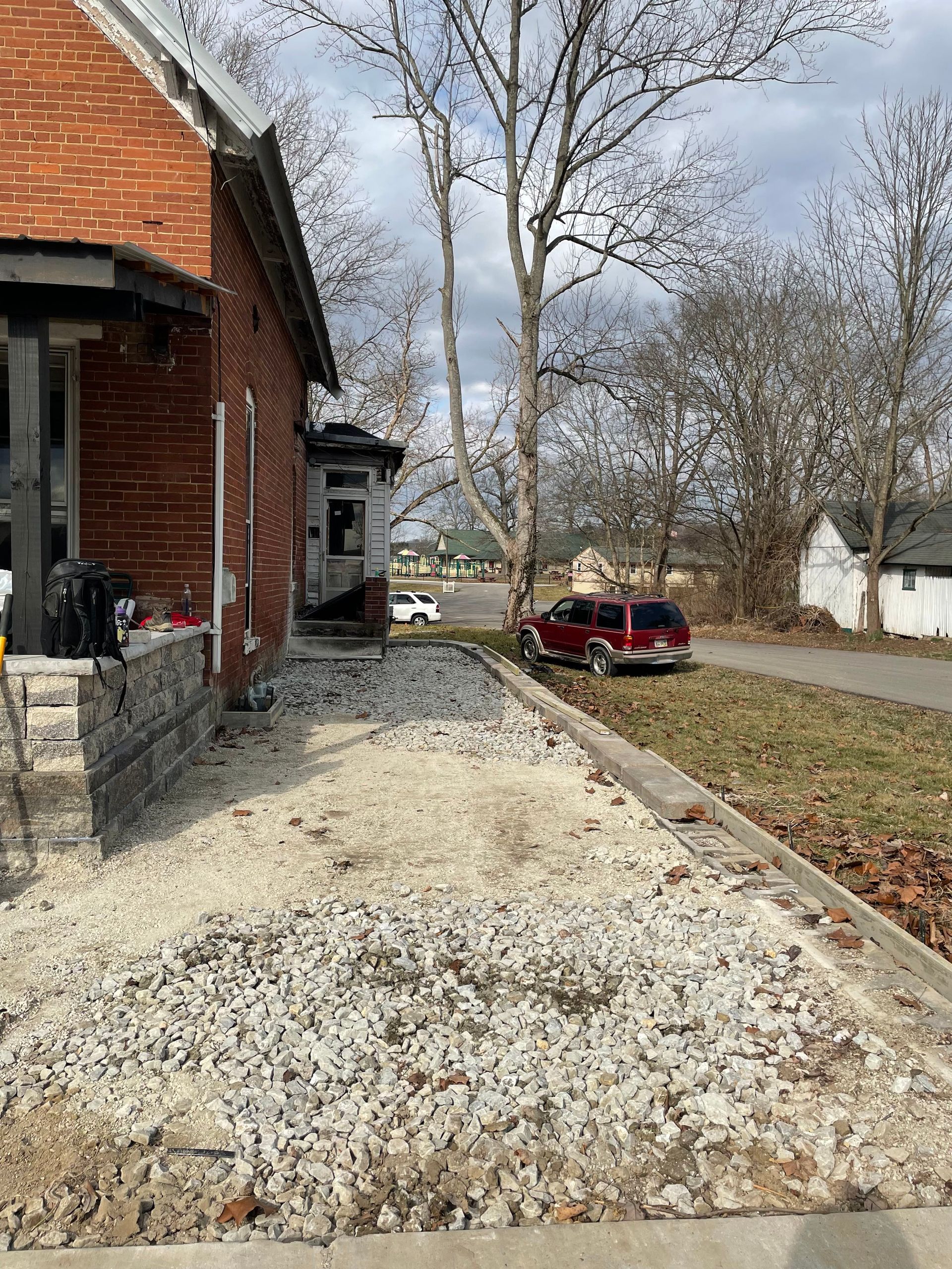 A red van is parked in front of a brick house.