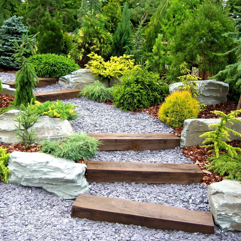 Professional Landscaping Service In Cincinnati, Oh A wooden staircase in a garden surrounded by rocks and plants.