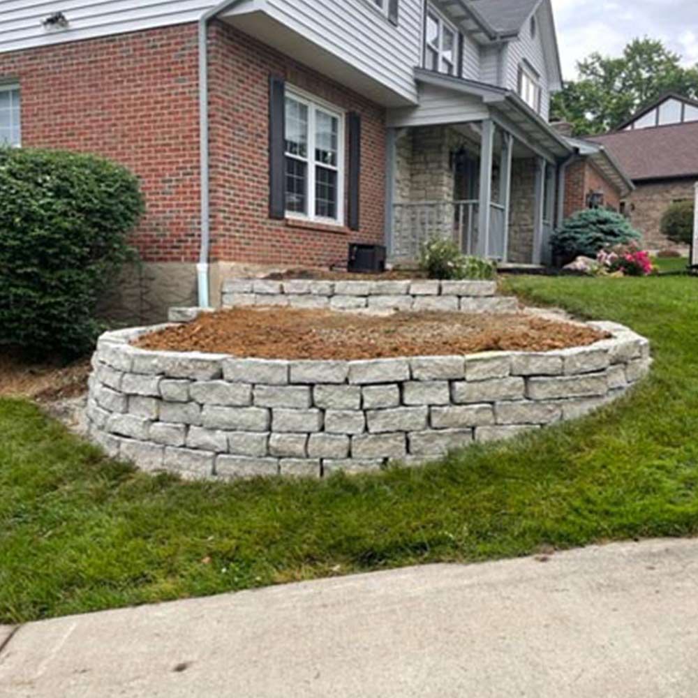 A brick wall is being built in front of a brick house.