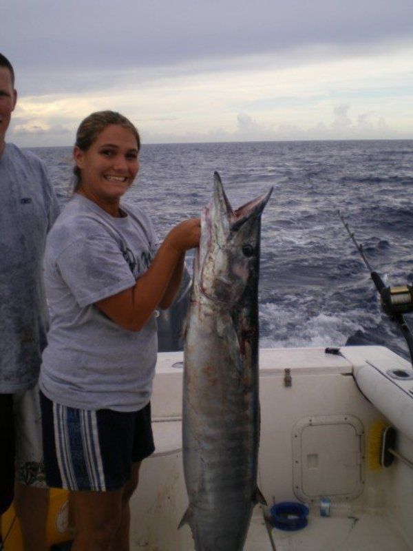 A man and a woman on a boat holding a large fish