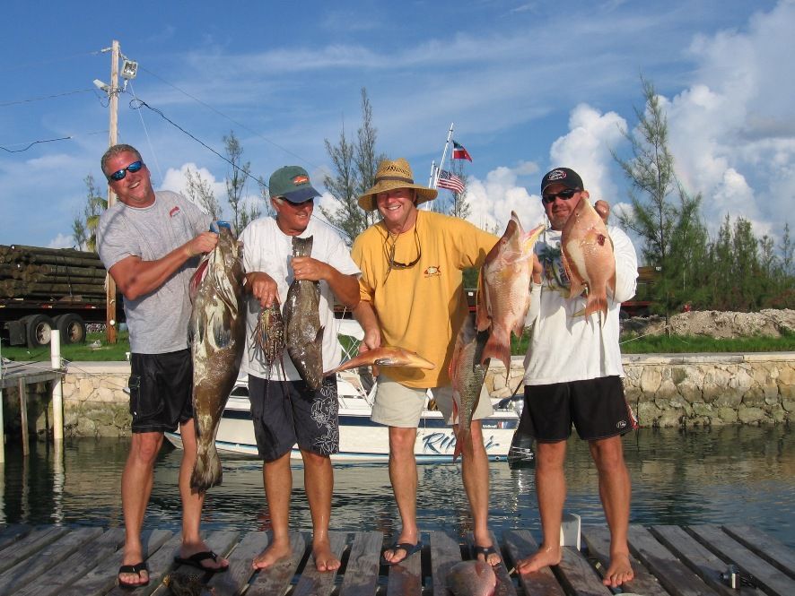 a group of men standing on a dock holding fish