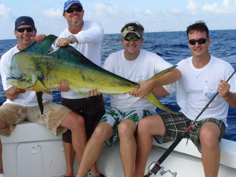 four men on a boat holding a large fish