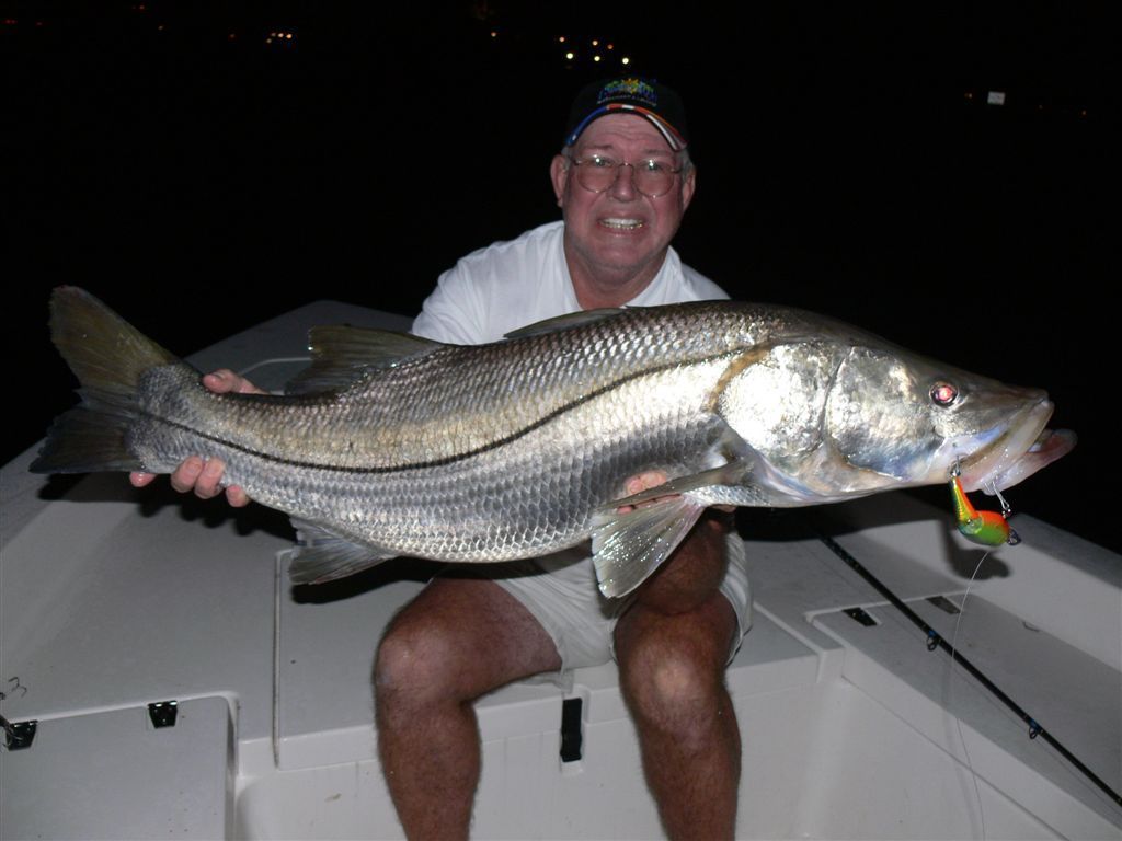 a man is sitting on a boat holding a large fish
