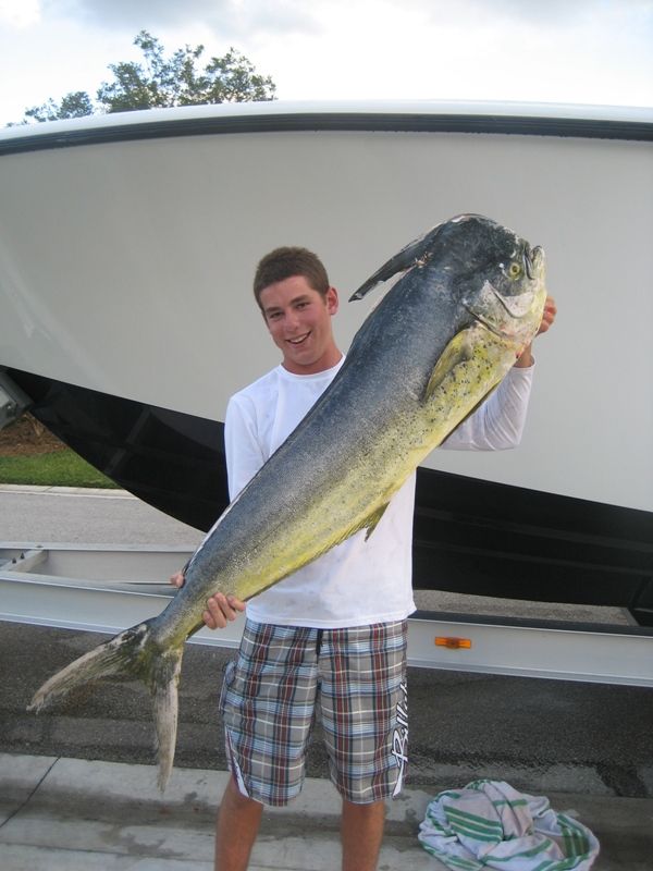 A man is holding a large fish in front of a boat
