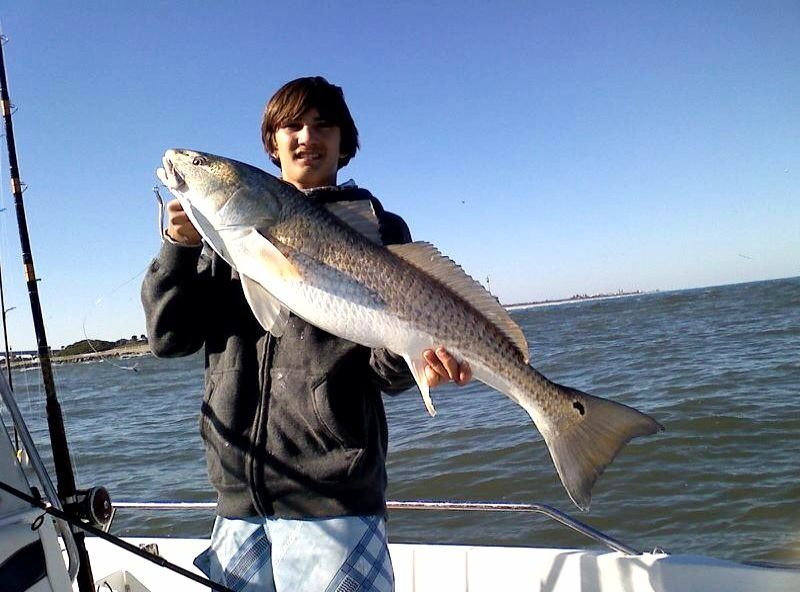 A young man is holding a large fish on a boat