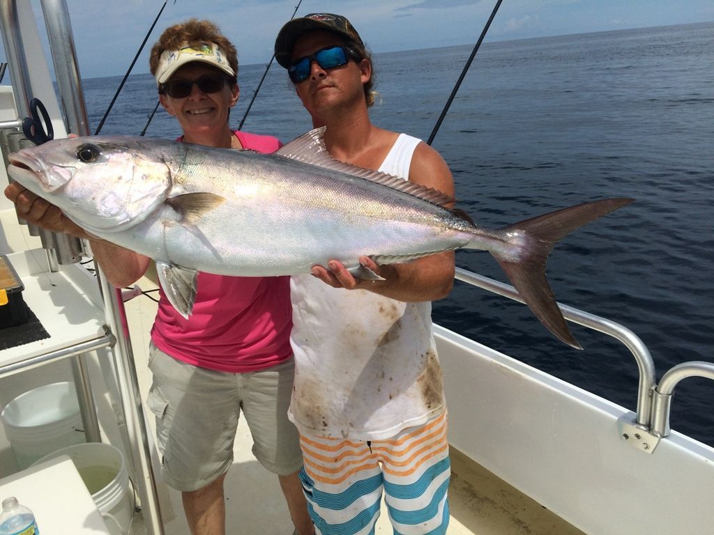 A man and a woman holding a large fish on a boat