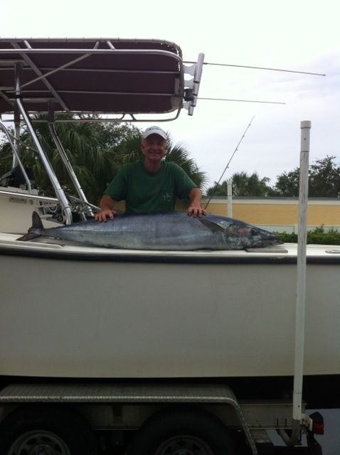 A man is standing on a boat holding a large fish