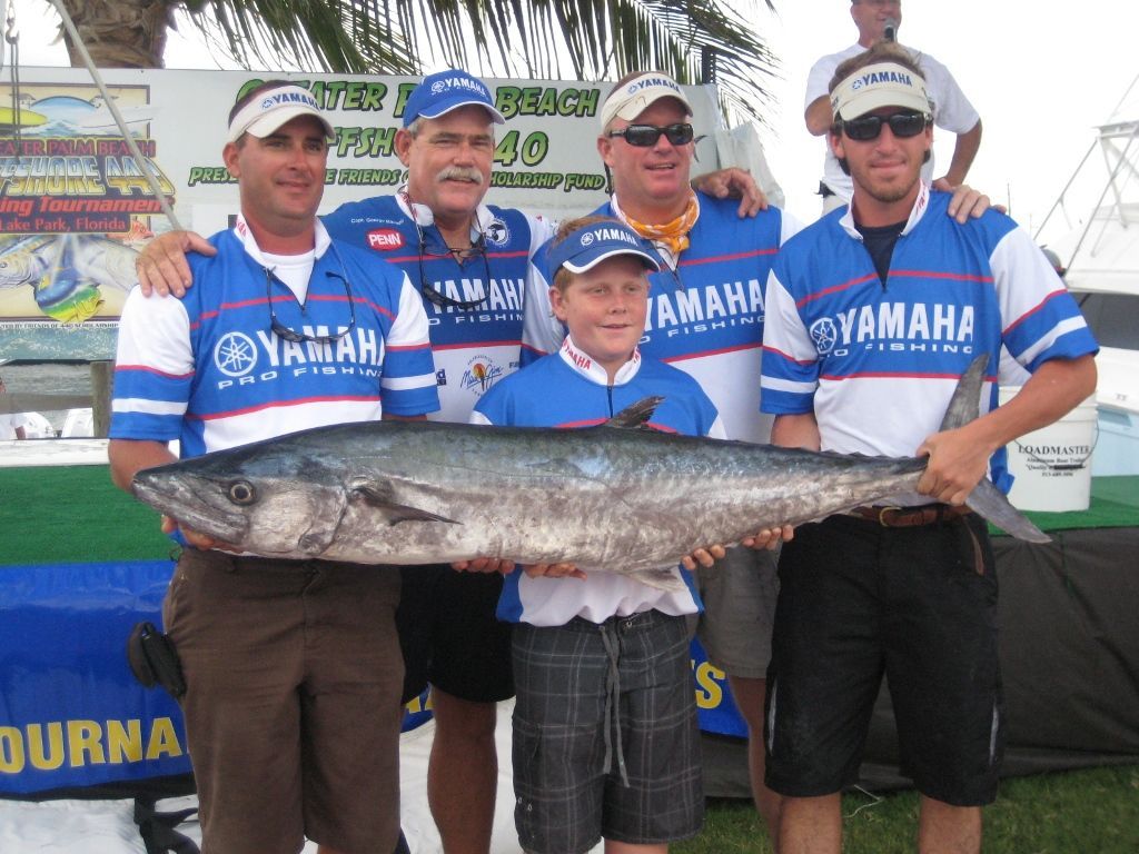A group of men wearing yamaha shirts holding a large fish