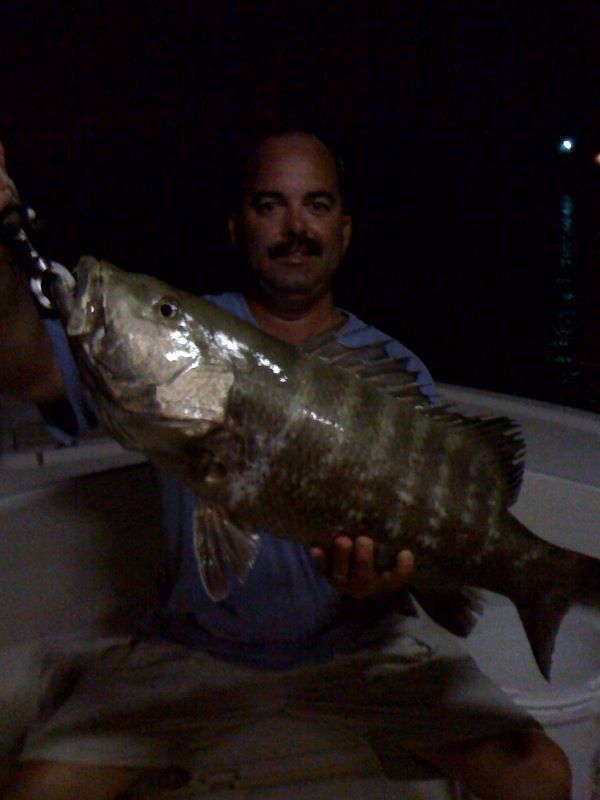 A man is holding a large fish in his hands