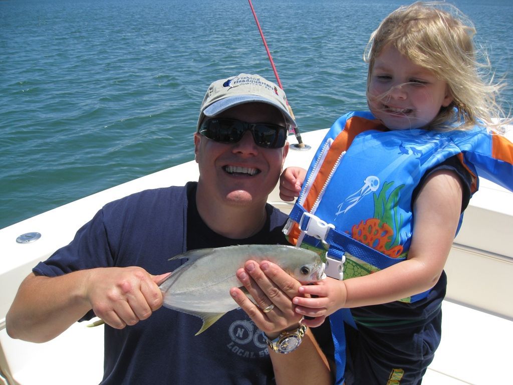 A man and a little girl on a boat holding a fish