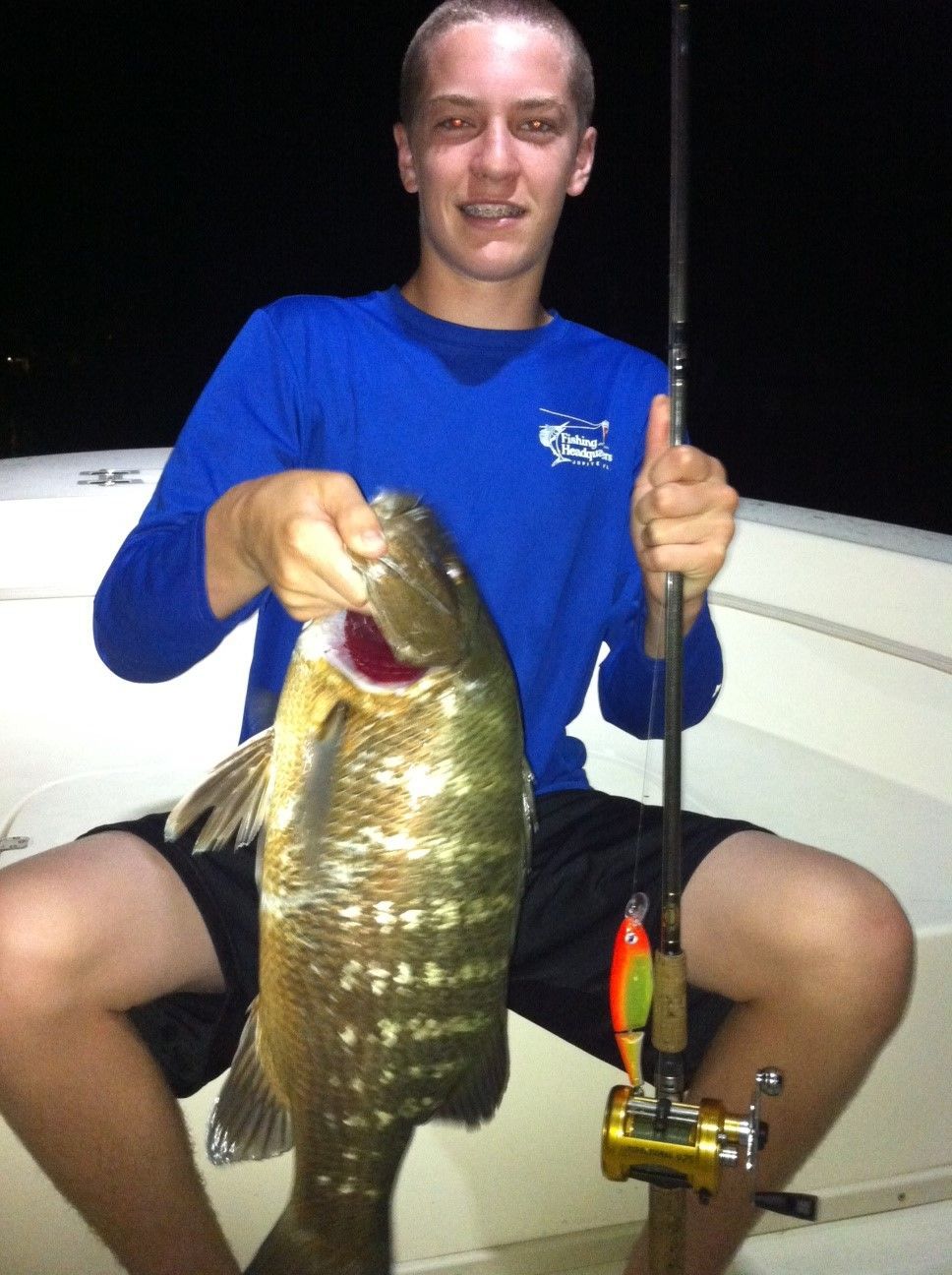 a man in a blue shirt is holding a large fish