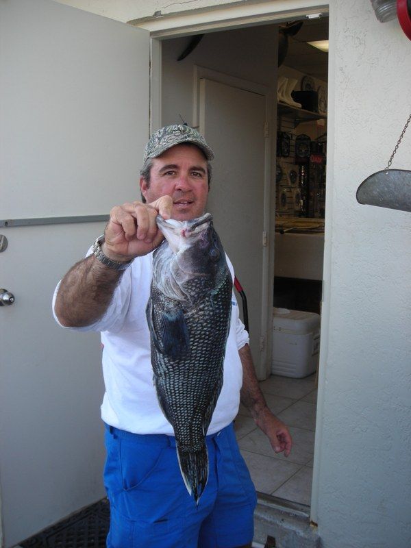 A man holding a large fish in front of a door