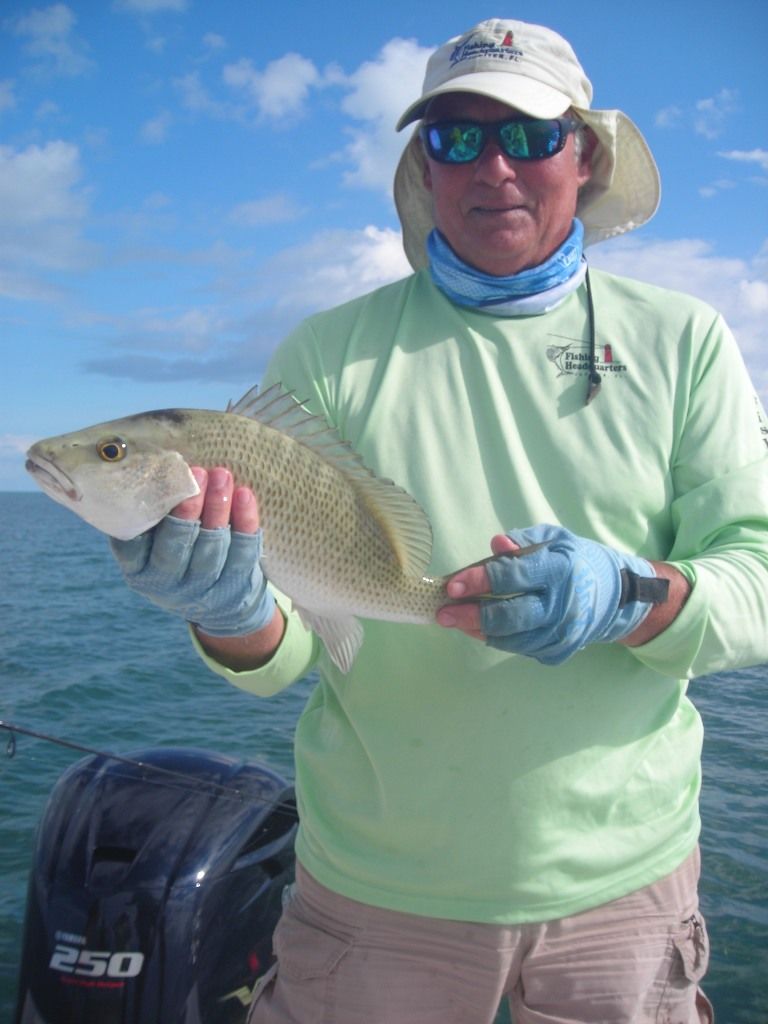 a man holding a fish in front of a 250 outboard motor