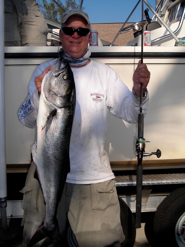 A man holding a large fish in front of a boat