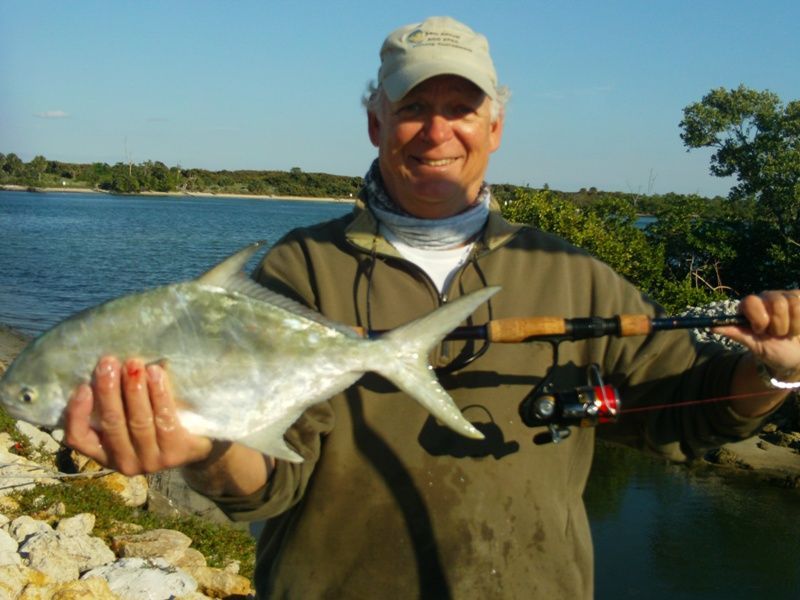 A man is holding a fish and a fishing rod