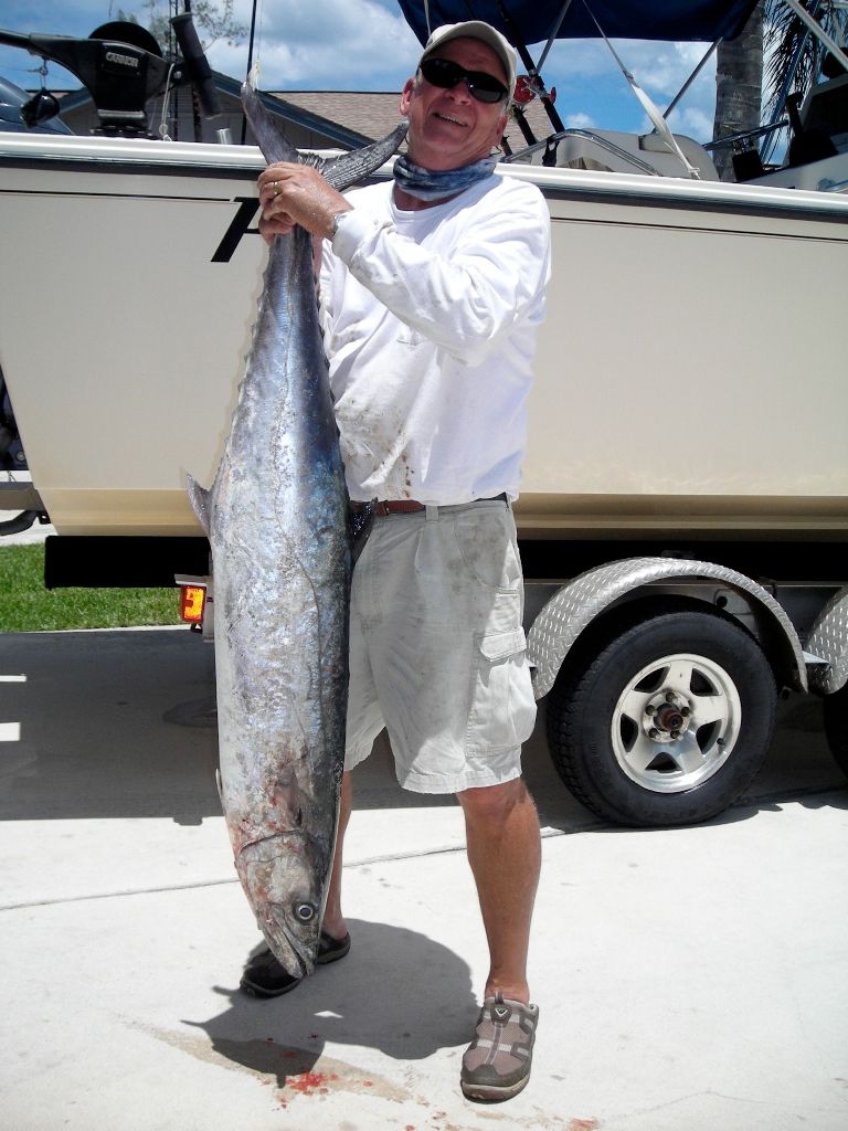 A man is holding a large fish in front of a boat