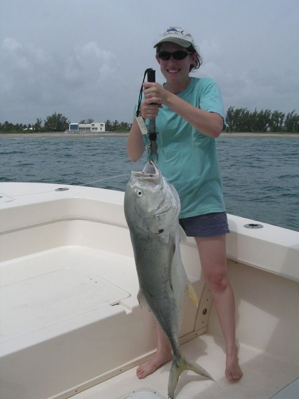 A woman is holding a large fish on a boat