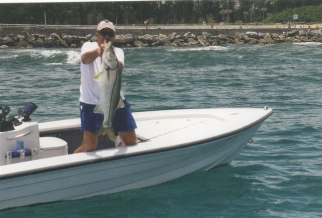 A man on a boat holding a large fish