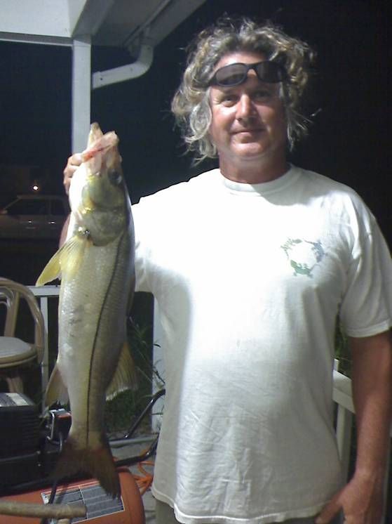 A man in a white shirt is holding a fish
