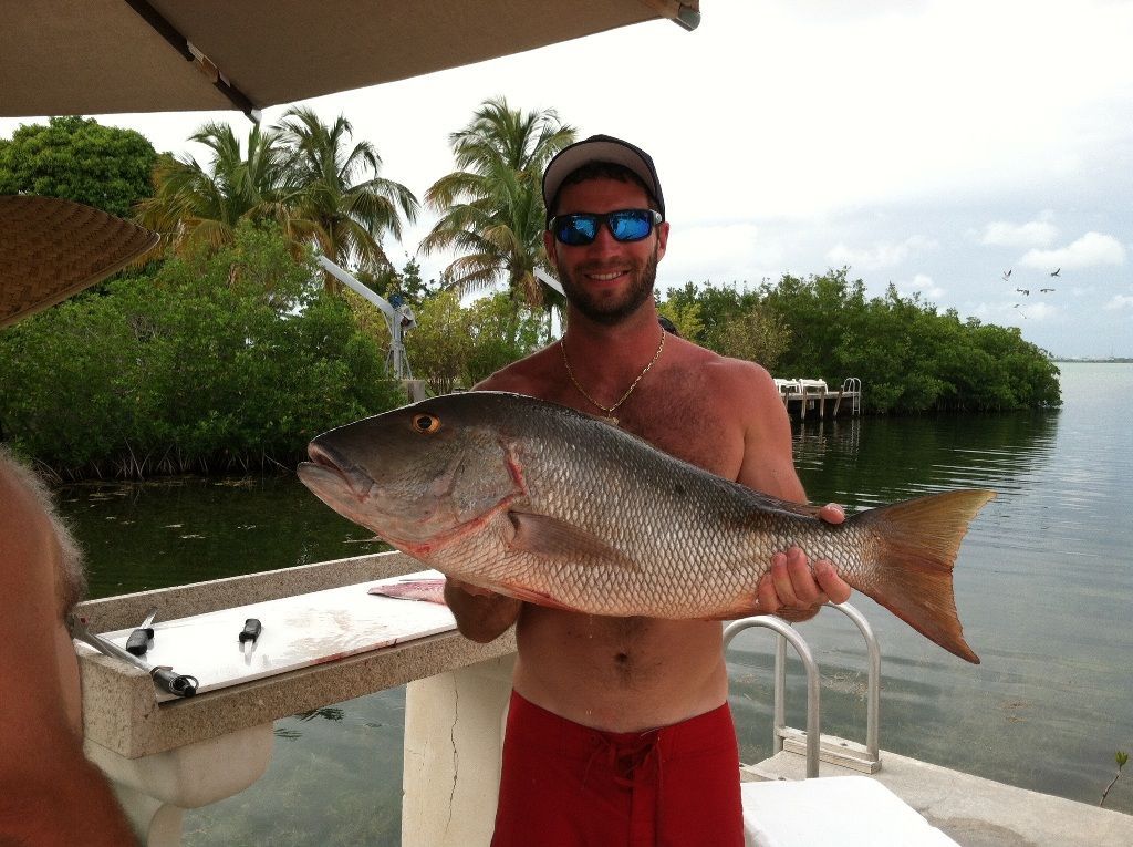 a man in red shorts is holding a large fish