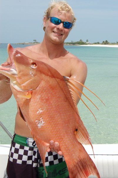 A man wearing sunglasses is holding a large red fish