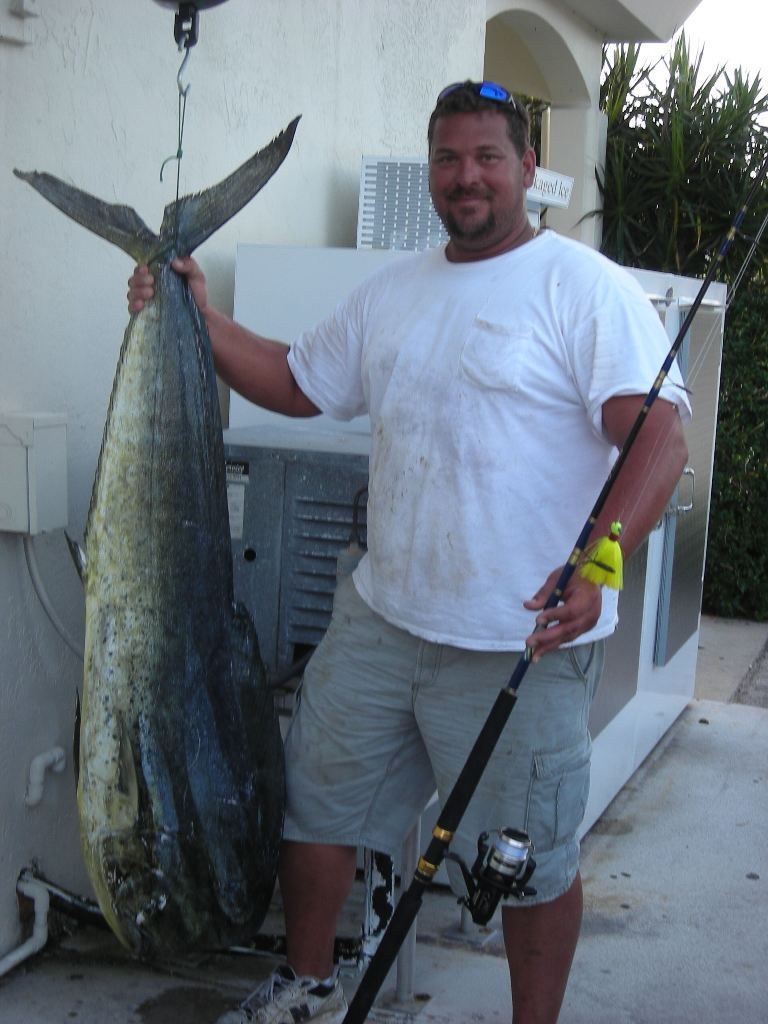 A man holding a large fish and a fishing rod