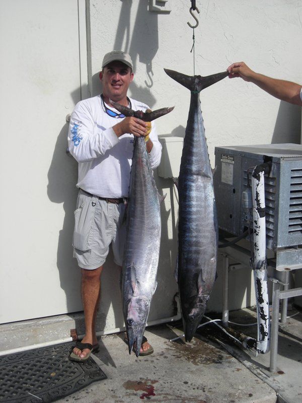 A man holding a large fish next to another fish