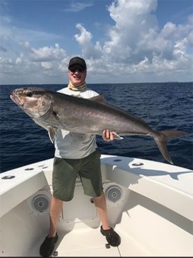 a man is standing on a boat holding a large fish .