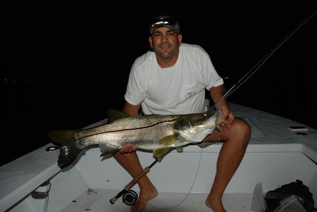 A man is sitting on a boat holding a large fish