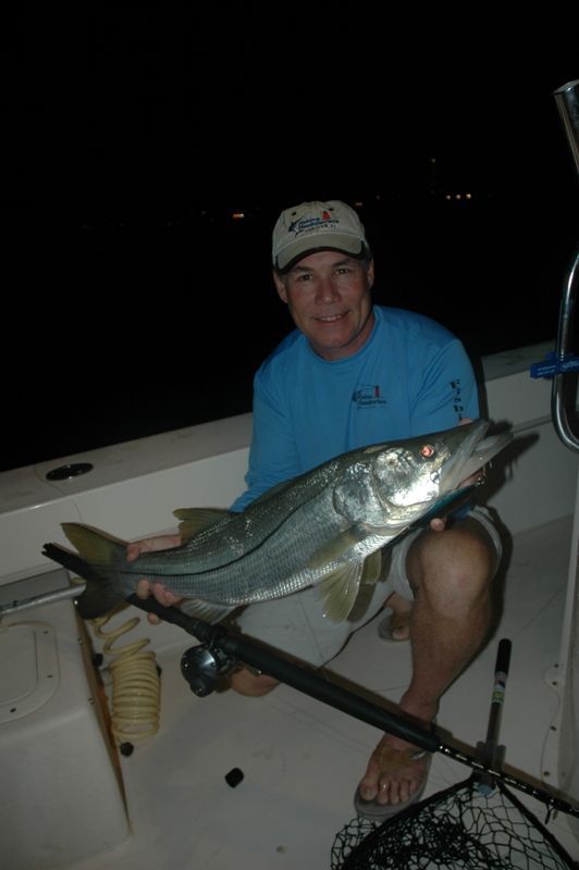 A man is sitting on a boat holding a large fish