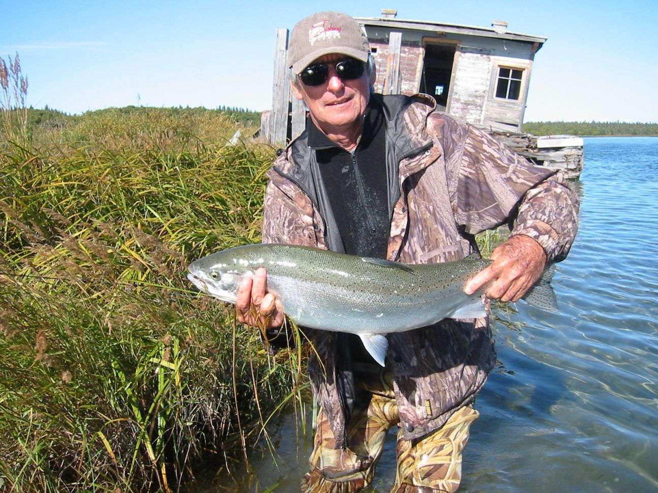 A man in a camo jacket is holding a large fish