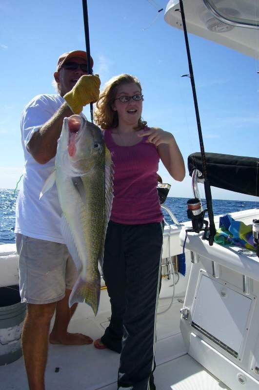 a man and a woman holding a large fish on a boat