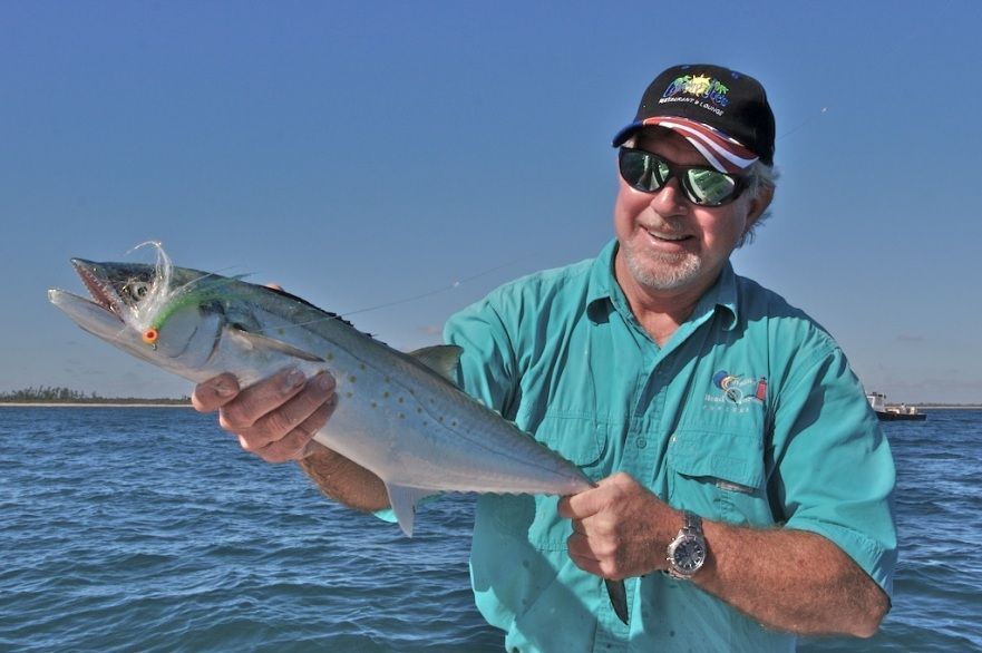 A man in a blue shirt is holding a fish in his hands