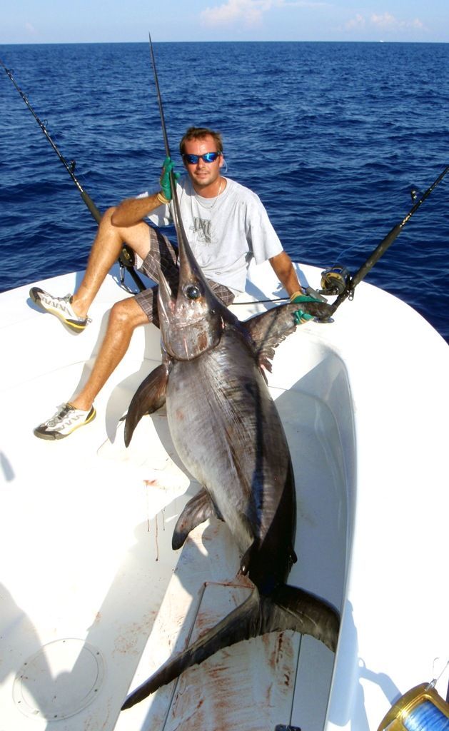 A man is sitting on a boat holding a large fish