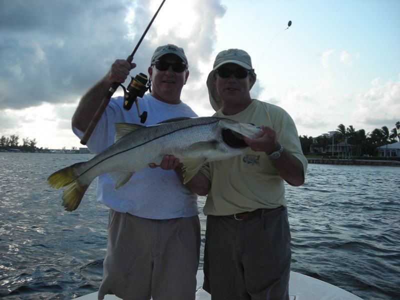 Two men on a boat holding a large fish