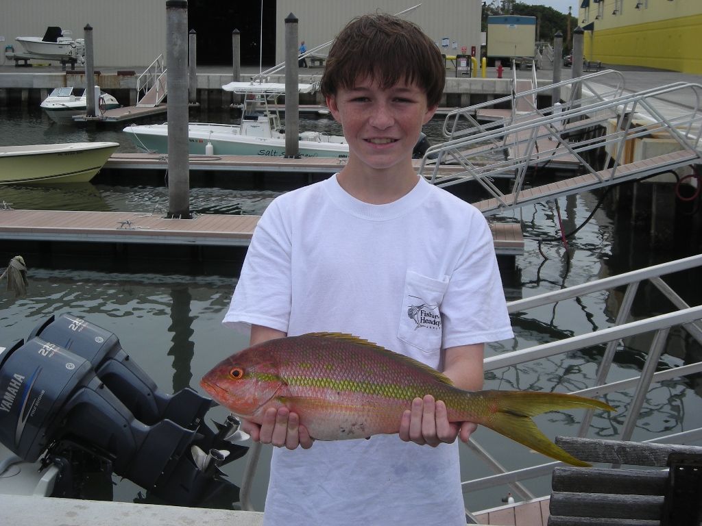 A boy in a white shirt is holding a fish