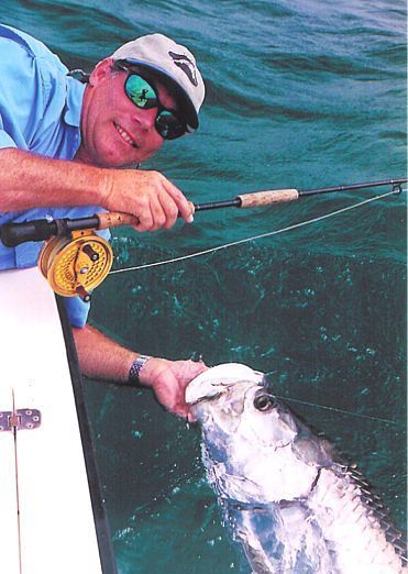 A man is fishing in the ocean and holding a fish
