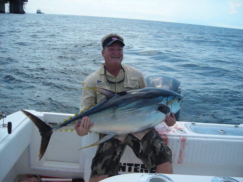 A man is holding a large fish on a boat that says inter