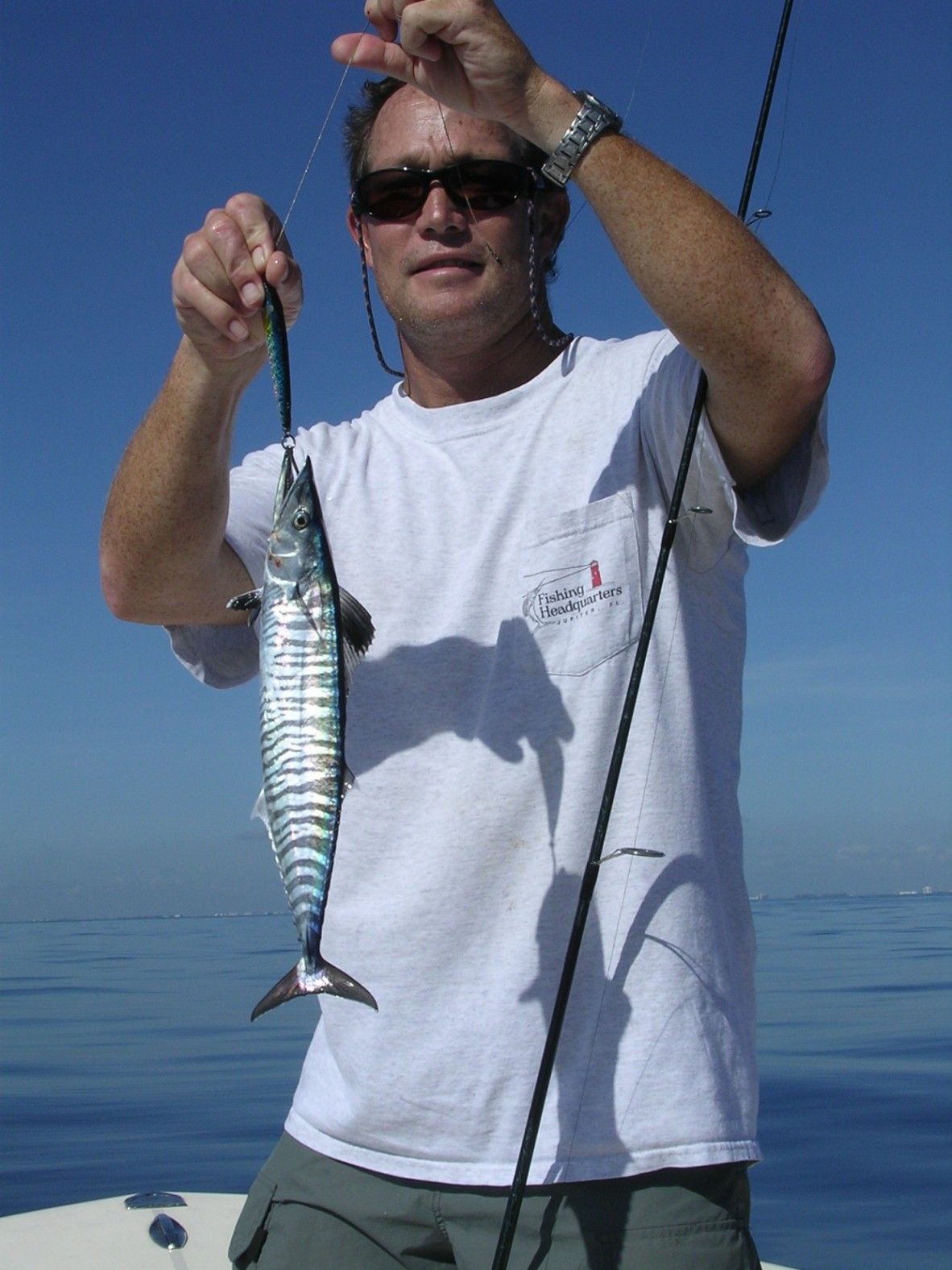 A man in a white shirt is holding a small fish