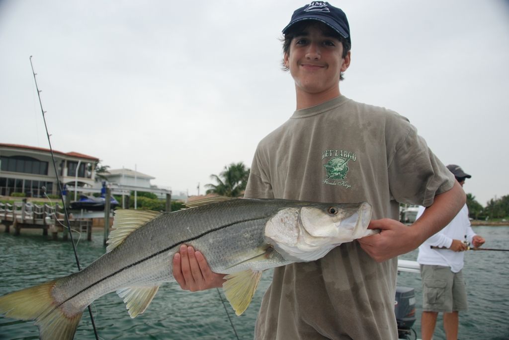 A young man holding a large fish in his hands