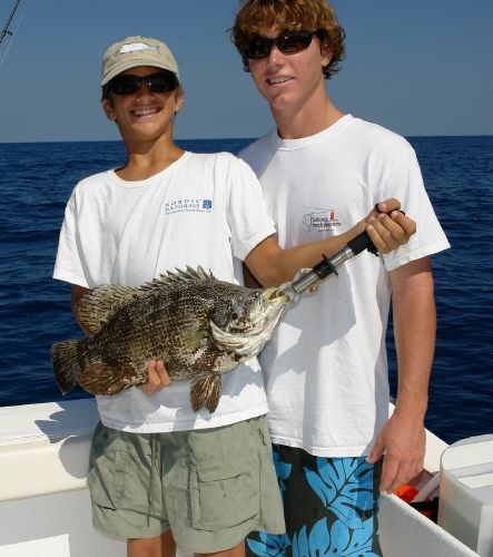 two young men holding a large fish on a boat