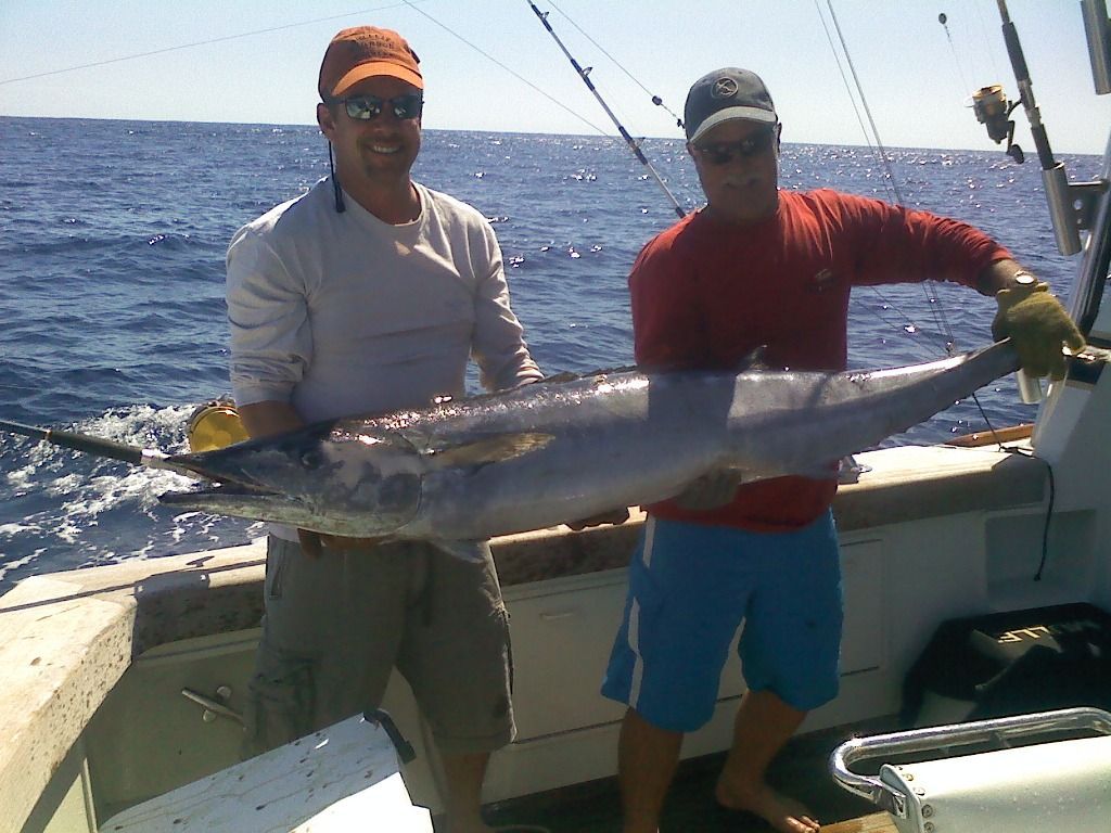 Two men on a boat holding a large fish